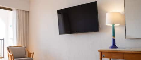 Una habitación de hotel con una cama, un televisor montado en la pared, un escritorio con una lámpara y una silla.