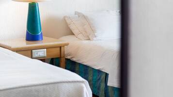 Quarto de hotel com cama, mesa de cabeceira com abajur e tomada.