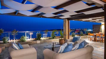 Un espacio al aire libre con vistas al mar, una mesa con una jarrón y una planta en maceta.