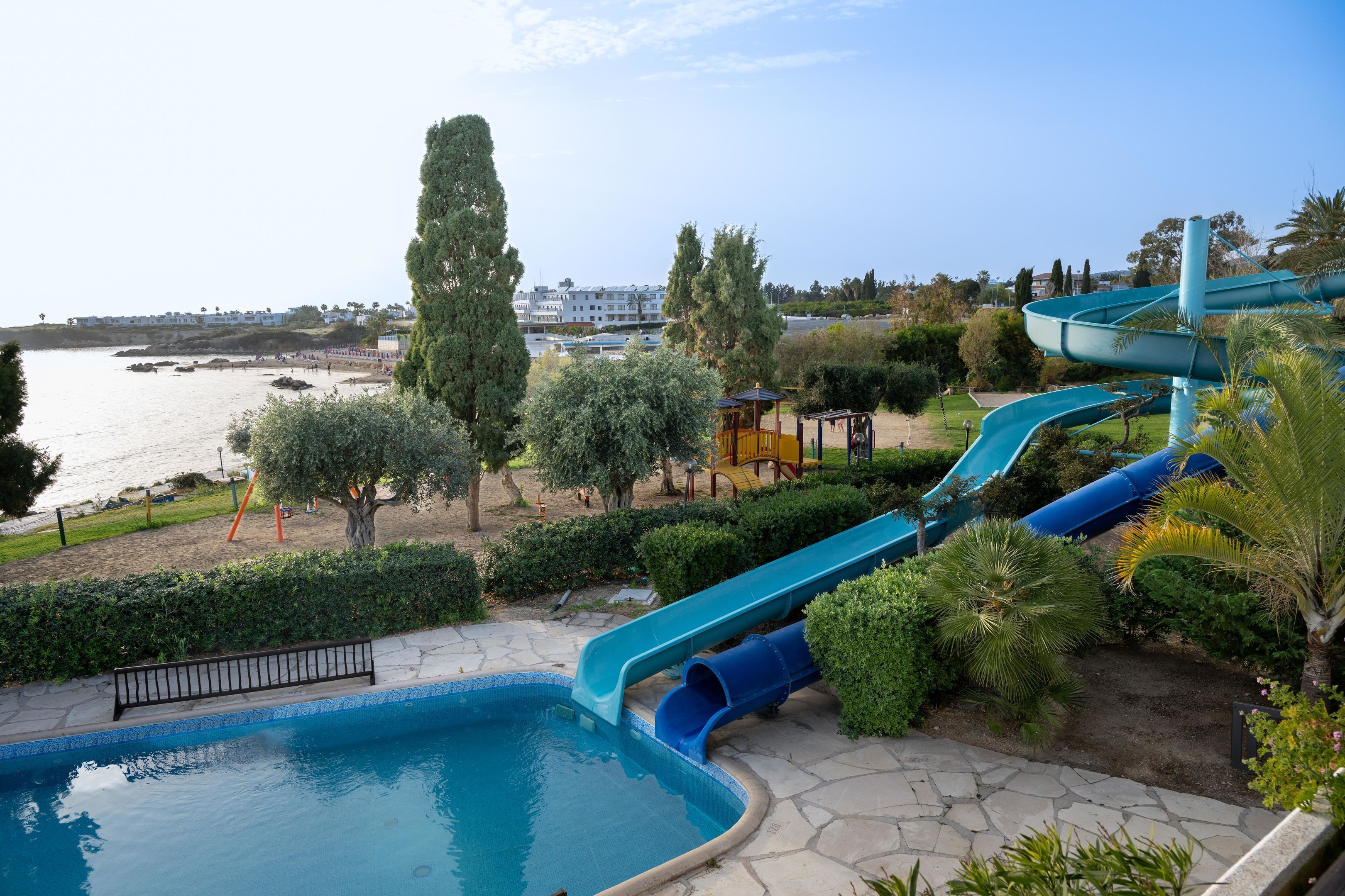 Una piscina con tobogán, una playa y vistas al mar.