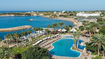 Un resort con una piscina grande, zona de playa y vista al océano.