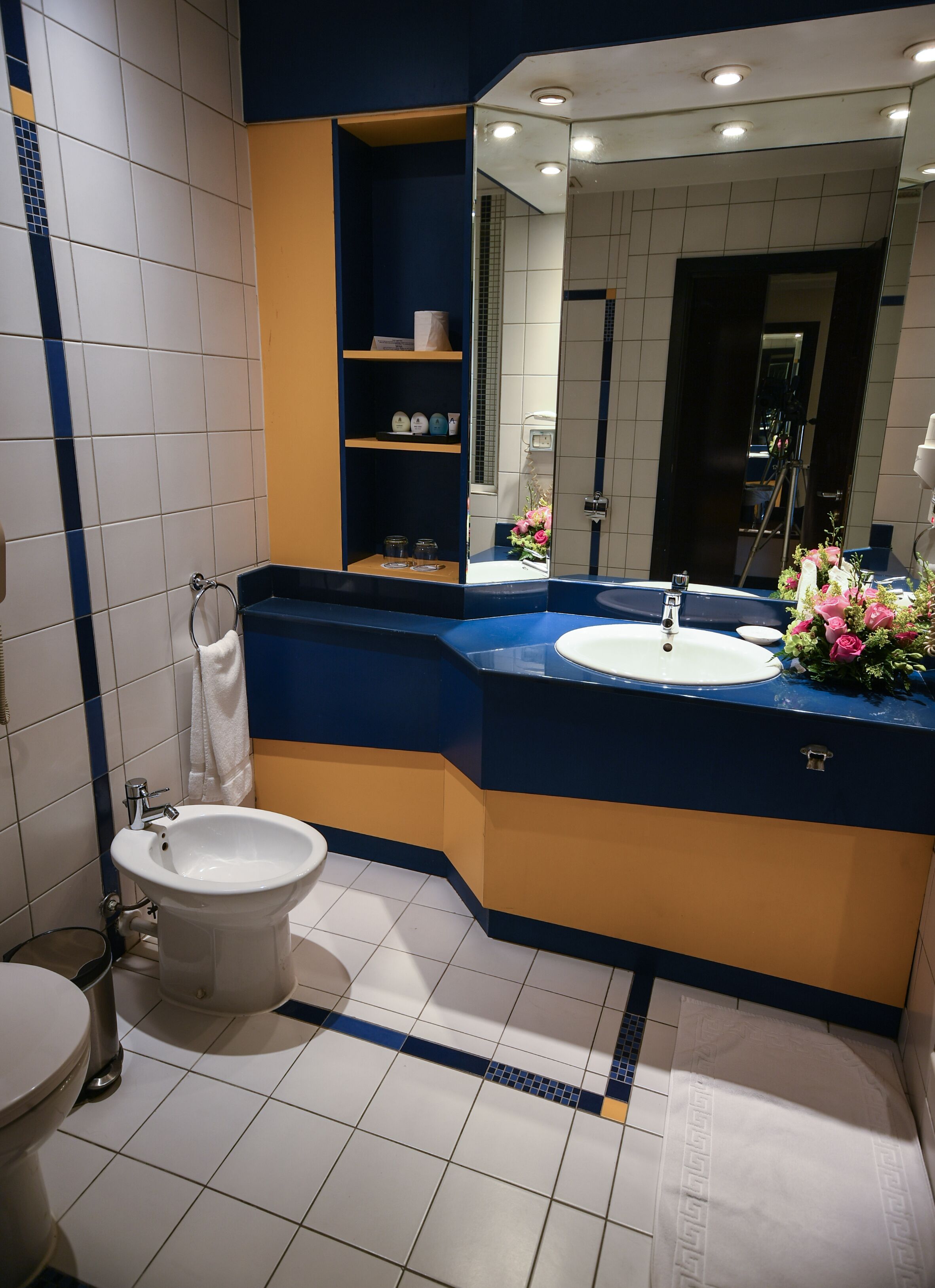Un baño moderno con un inodoro blanco, un lavabo con encimera azul y un espejo sobre el lavabo.