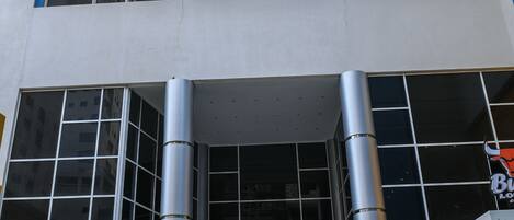 A modern building with a glass facade, large windows, and a set of stairs leading to the entrance.