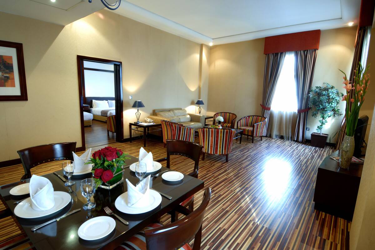 A hotel room with a dining area, a sofa, and a living area.