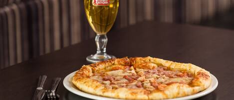 Pizza en un plato blanco, con una jarra de cerveza al fondo.