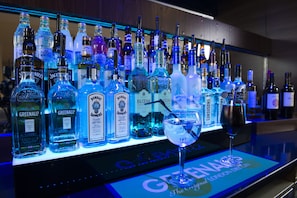 A bar with various liquor bottles and two glasses of cocktails.