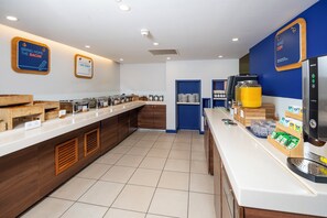 A buffet-style breakfast area with a coffee machine, condiment dispensers, and a sign that says 'Bring home the bacon.' - Holiday Inn Express London - Dartford by IHG (Dartford)