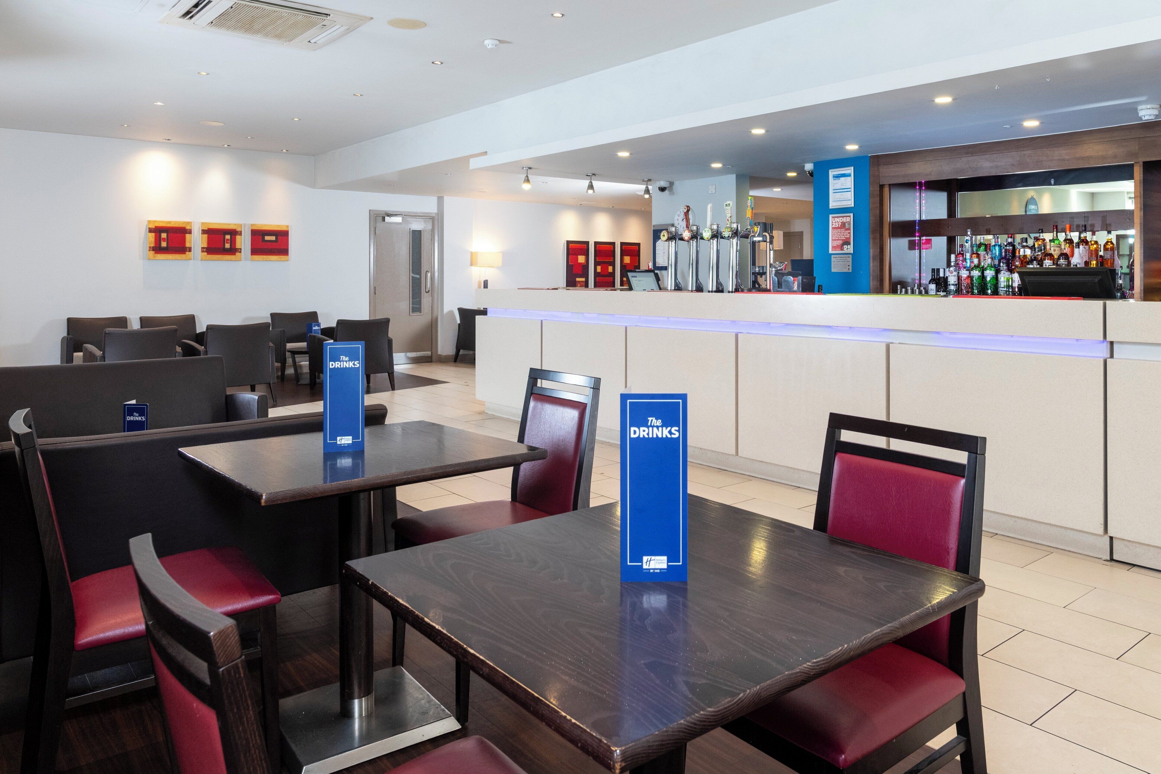 A hotel lobby with a bar area, seating arrangements, and a reception desk.