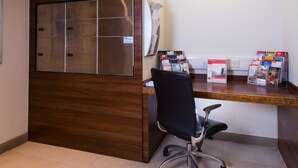 A modern office space with a wooden partition, a desk with a chair, and informational brochures.