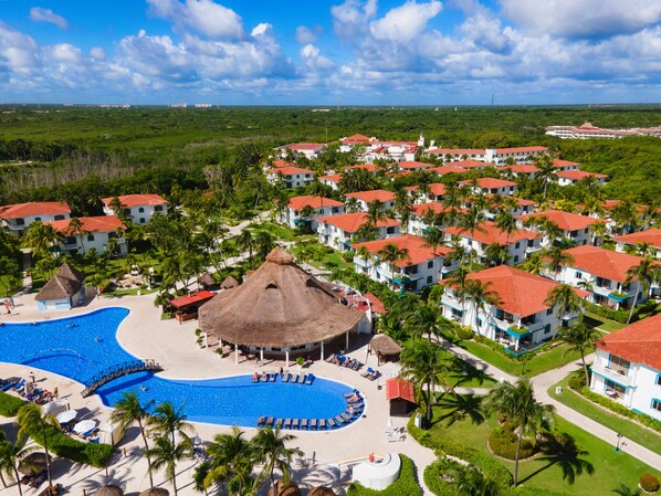 Relax by the resort's inviting pool surrounded by lush greenery and palm trees.