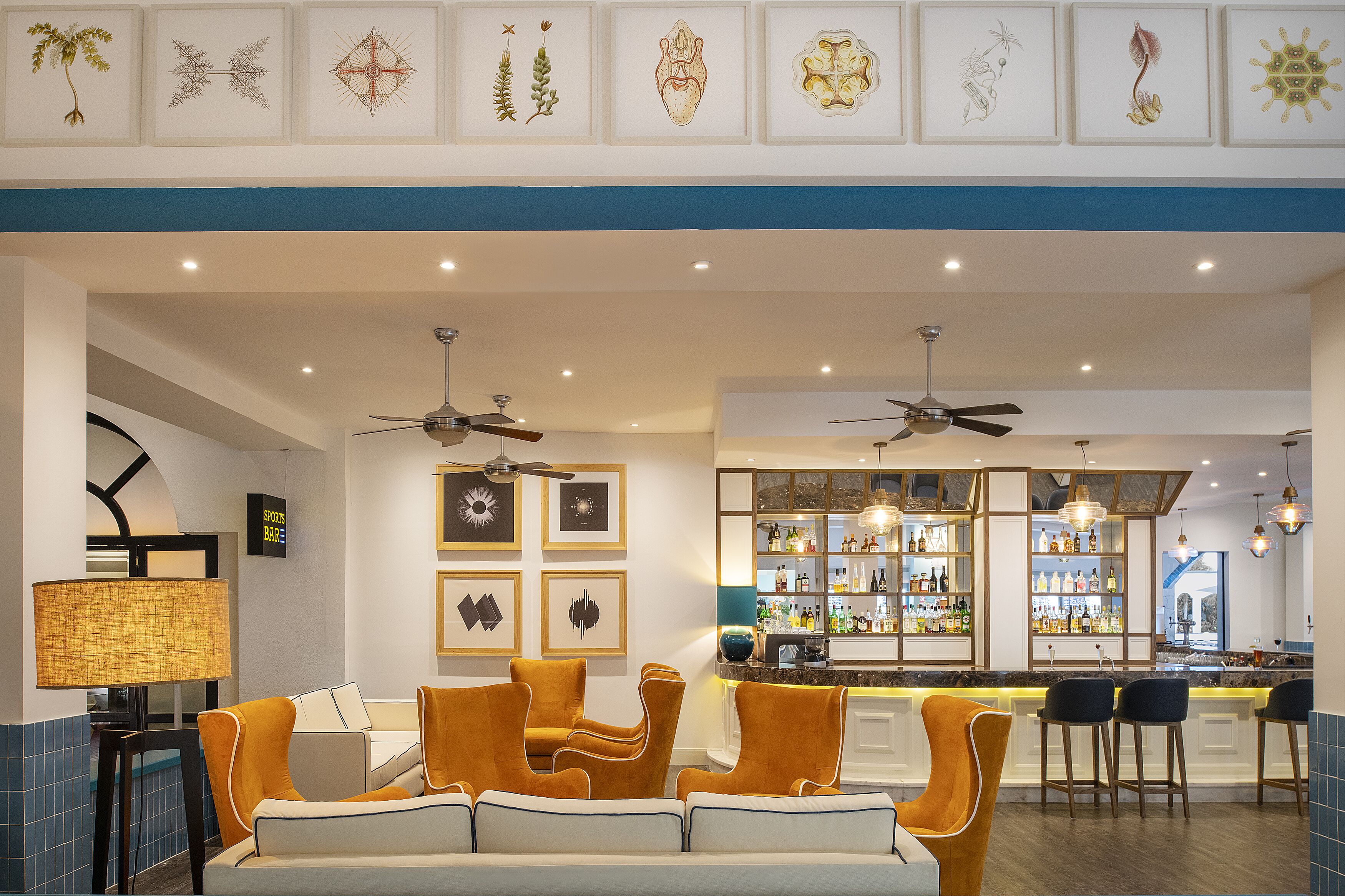Un hall d’hôtel moderne doté d’un bar, de différents espaces de détente et de ventilateurs de plafond.
