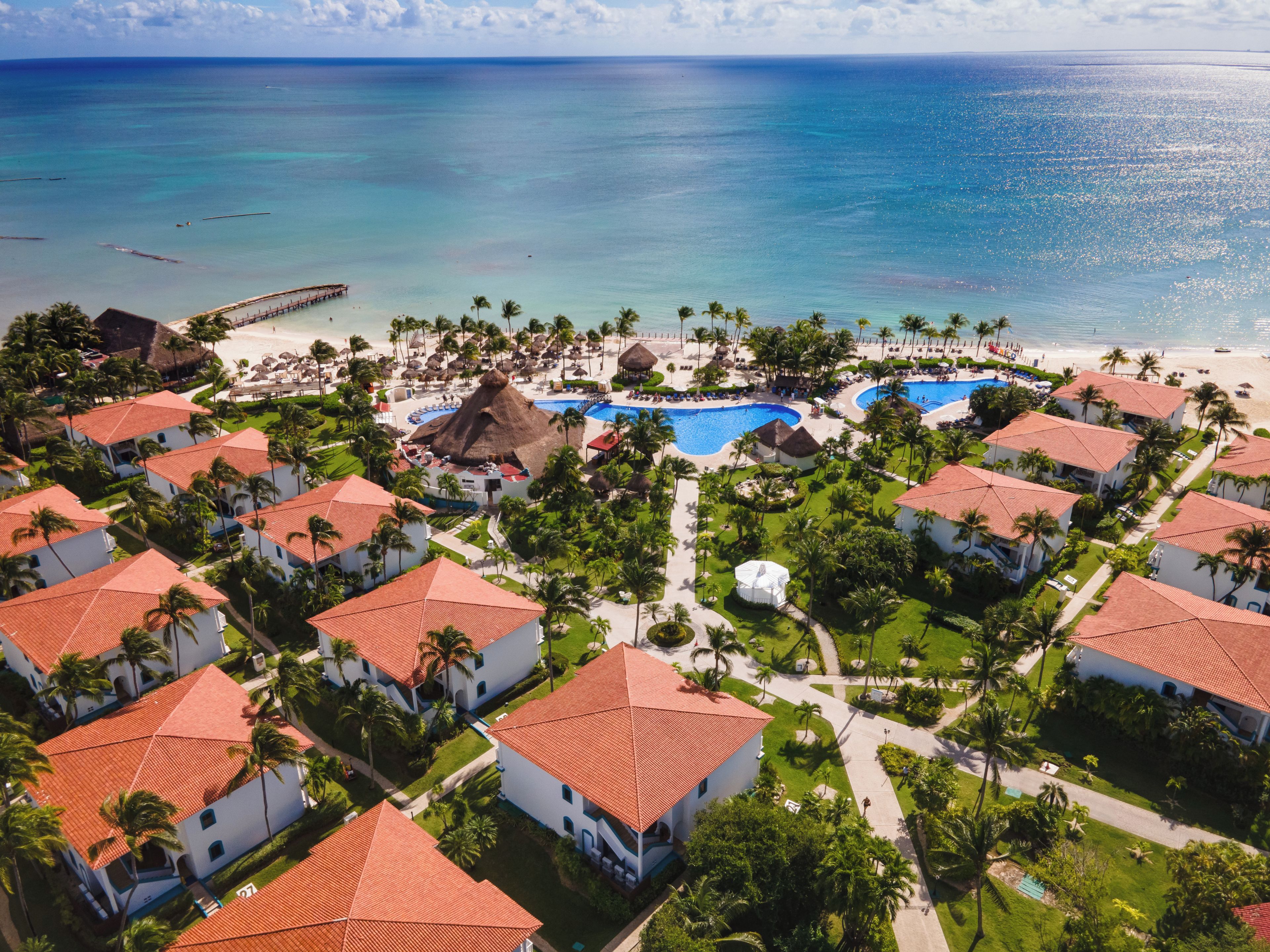 Ein Resort mit mehreren Gebäuden, einem großen Schwimmbad und einem Strand.