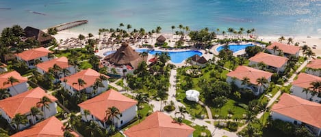 Ein Resort mit mehreren Gebäuden, einem großen Schwimmbad und einem Strand.