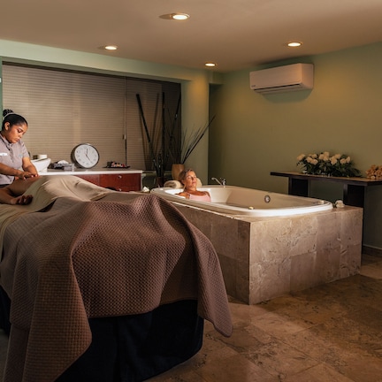 A modern bathroom with a large bathtub, a massage table, and a vanity with a sink.
