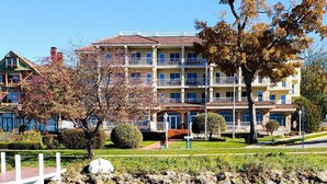 Un hotel con varios balcones, vista despejada al agua y un jardín bien cuidado.