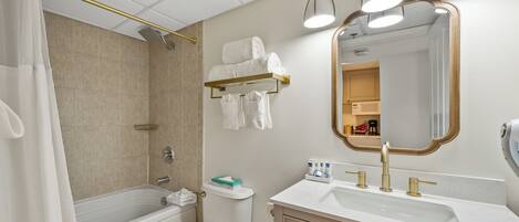A bathroom with a bathtub, toilet, sink, and a mirror.