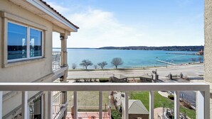 Un balcón con vistas a un lago, un muelle y una orilla distante.