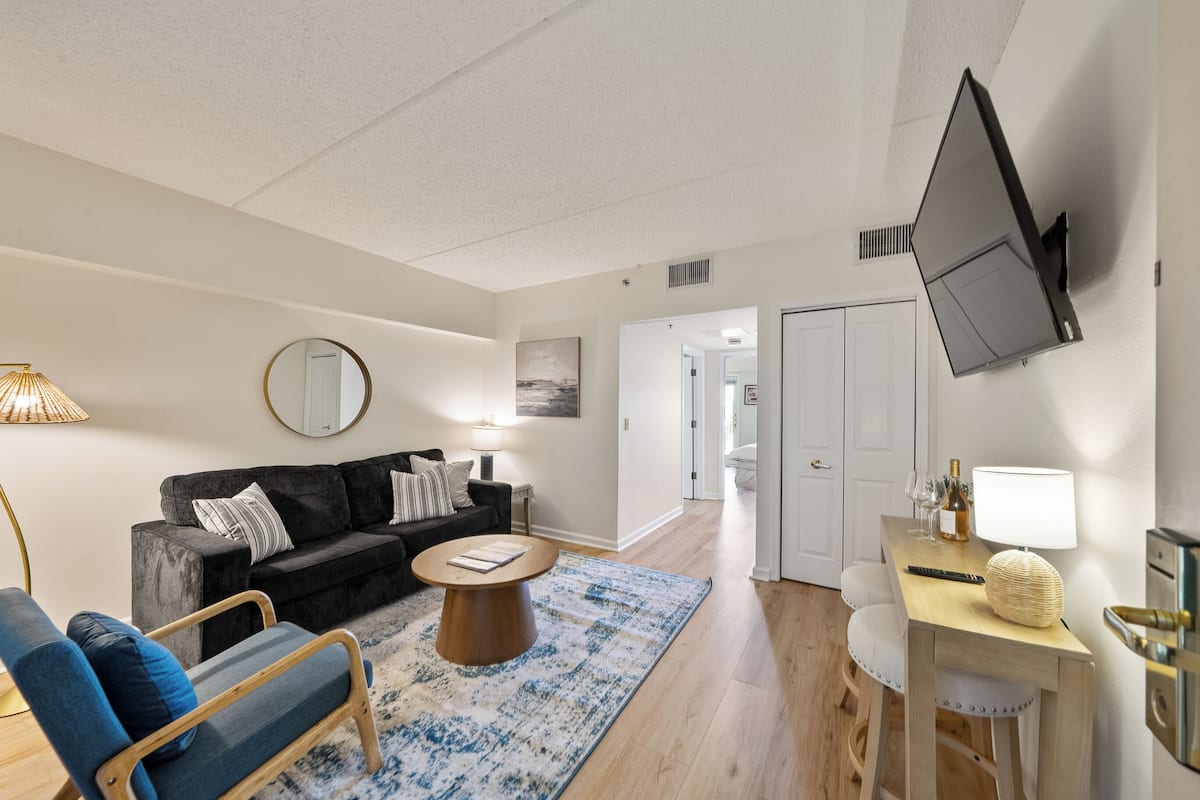 A modern living room with a sofa, coffee table, and a TV mounted on the wall.