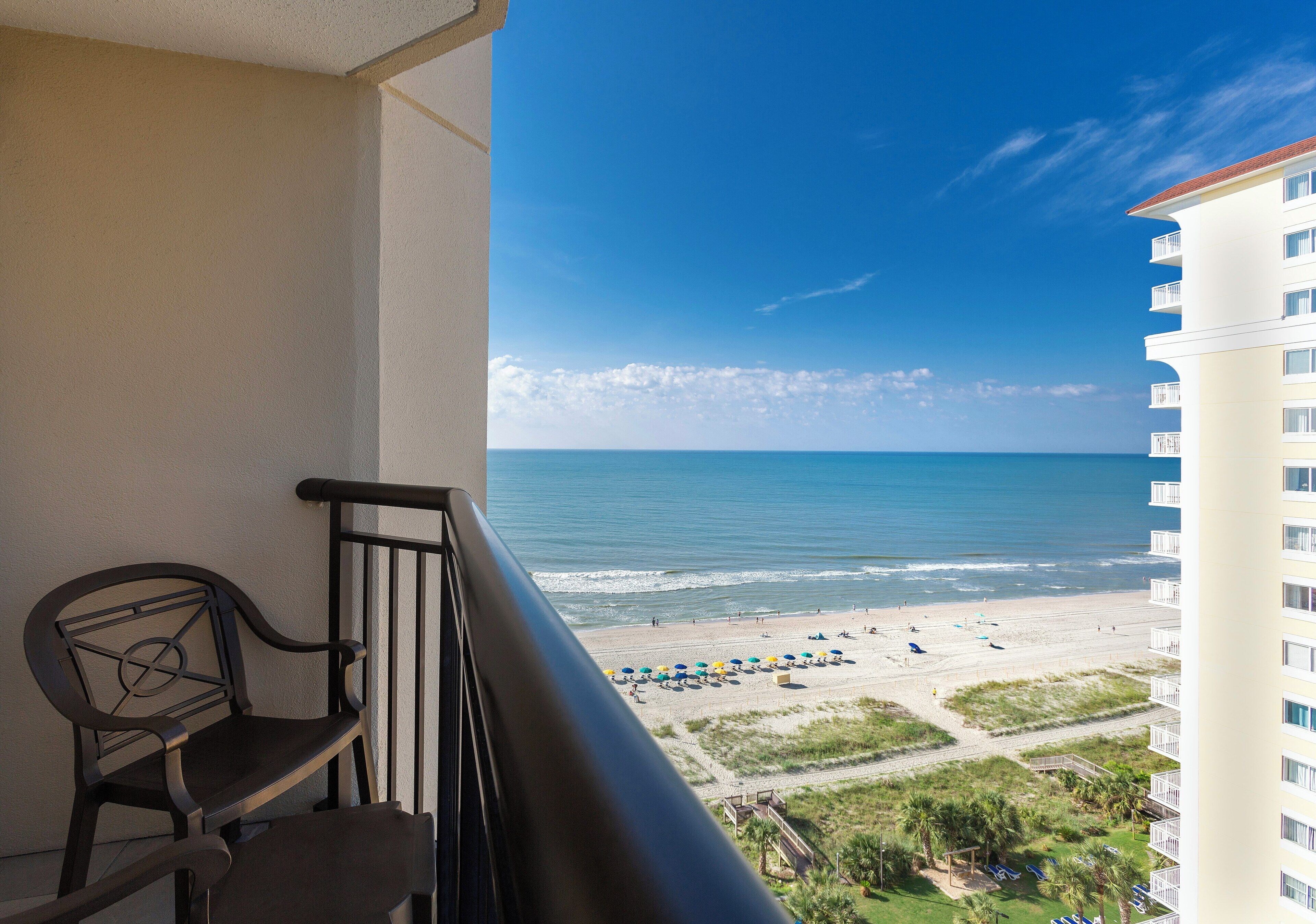 A balcony with a view of the beach and ocean.