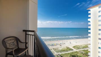 A balcony with a view of the beach and ocean.