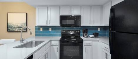 Una cucina moderna con mobili bianchi, un piano cottura nero e un frigorifero nero.