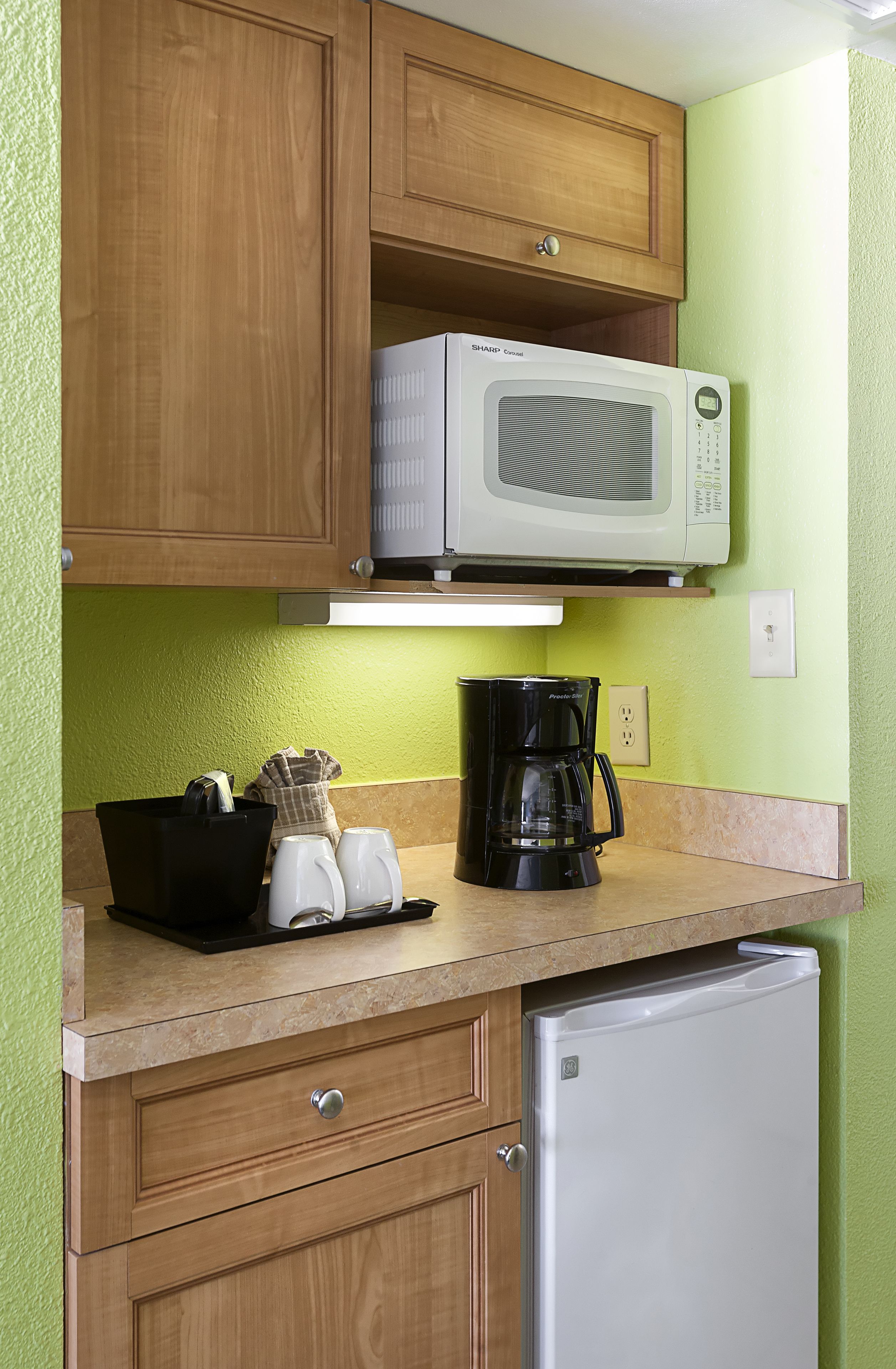 A kitchenette with a microwave, coffee maker, and refrigerator.