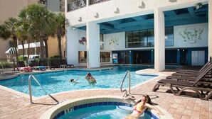 Una piscina con sillones de descanso y palmeras.