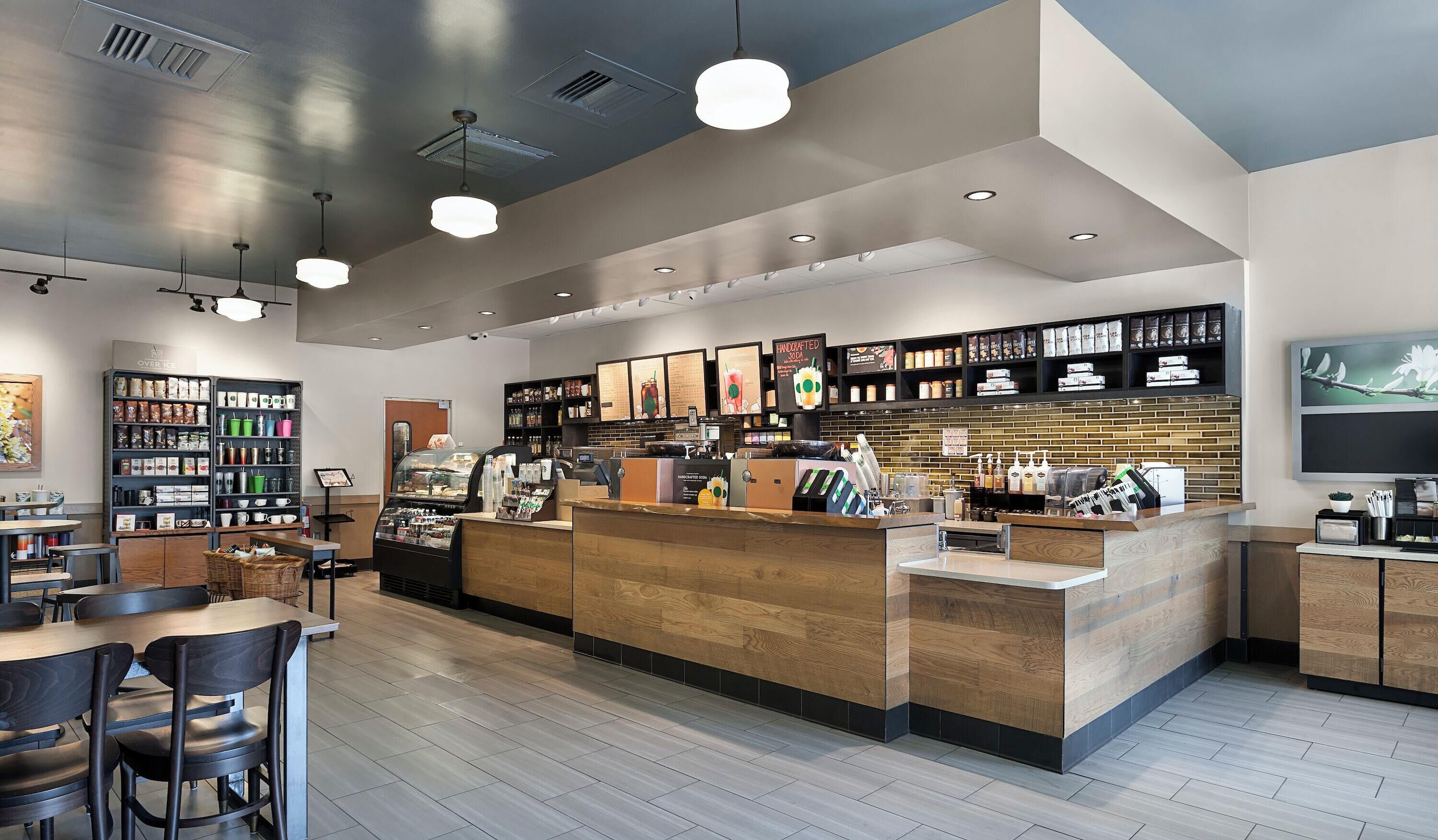 A modern coffee shop interior with a wooden counter, seating area, and various coffee-related products on shelves.