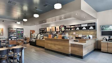 A modern coffee shop interior with a wooden counter, seating area, and various coffee-related products on shelves.