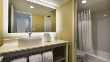 A bathroom with a sink, mirror, towel rack, and a shower area.