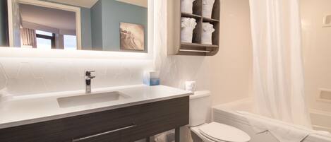 A modern bathroom with a white sink, dark wooden vanity, a white toilet, and a shower with a white curtain.