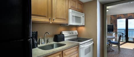 A kitchen with wooden cabinets, a microwave, a stove, and a sink.