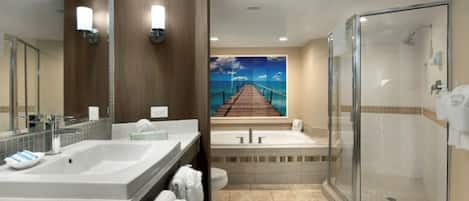 A modern bathroom with a large mirror, two sinks, a bathtub, and a glass shower enclosure.