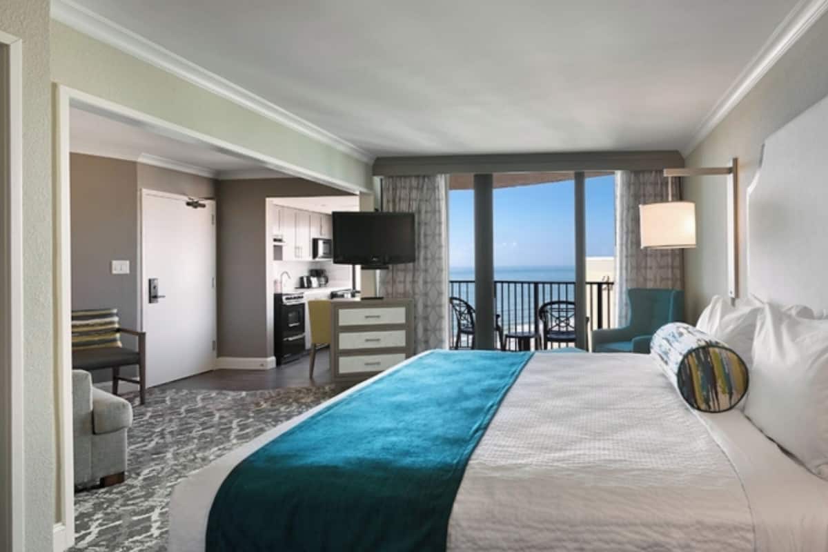 Una camera d'albergo con un letto, una scrivania, una sedia e vista sull'oceano.