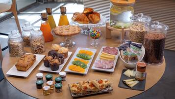 A breakfast buffet with various pastries, fruits, cheeses, and condiments.