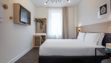 Una camera d'albergo moderna con un grande letto, una TV a parete, un comodino, una sedia e un lampadario.