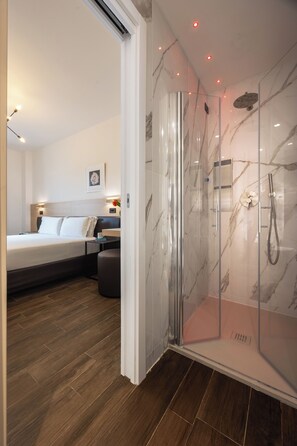 Relax in a spacious room with a large bed, bedside table, and glass-enclosed shower area.