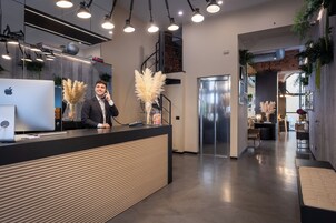 A modern reception area with a counter, a laptop, and a decorative plant.