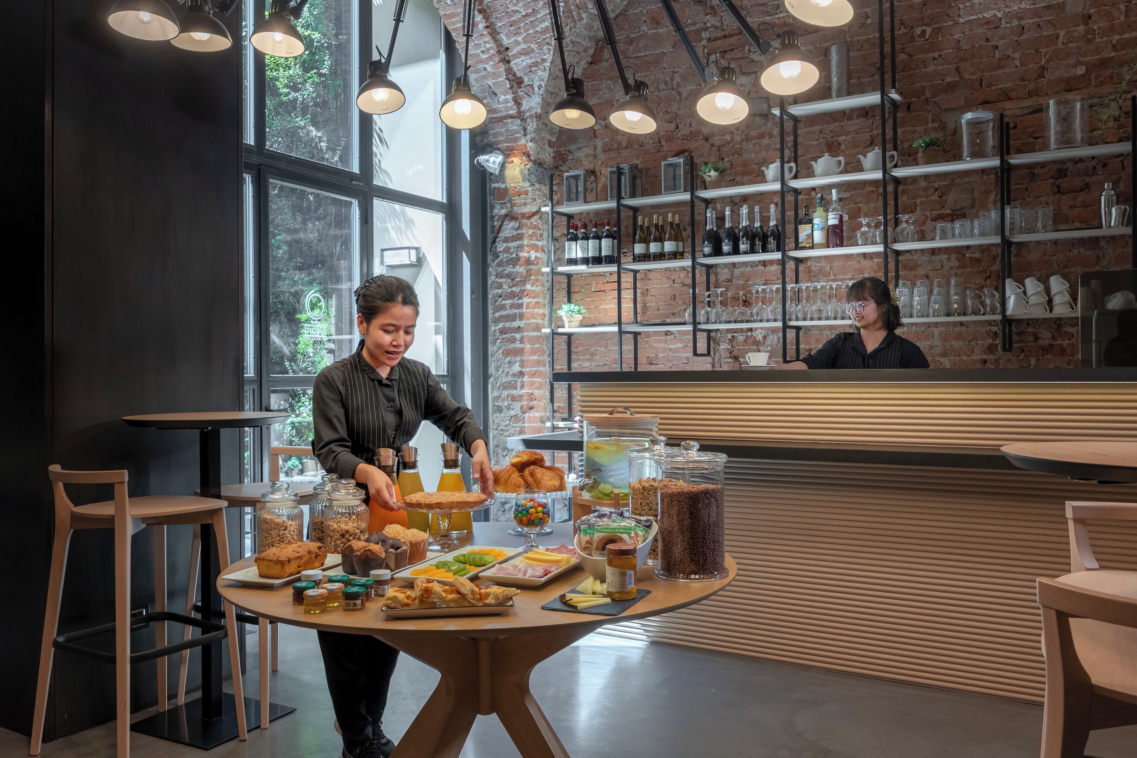Ein Frühstücksbuffet mit verschiedenen Speisen sowie ein Barbereich mit Regalen voller Flaschen und Gläsern.