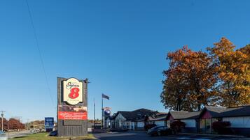 A Super 8 motel with a large sign, outdoor seating, and a flag.
