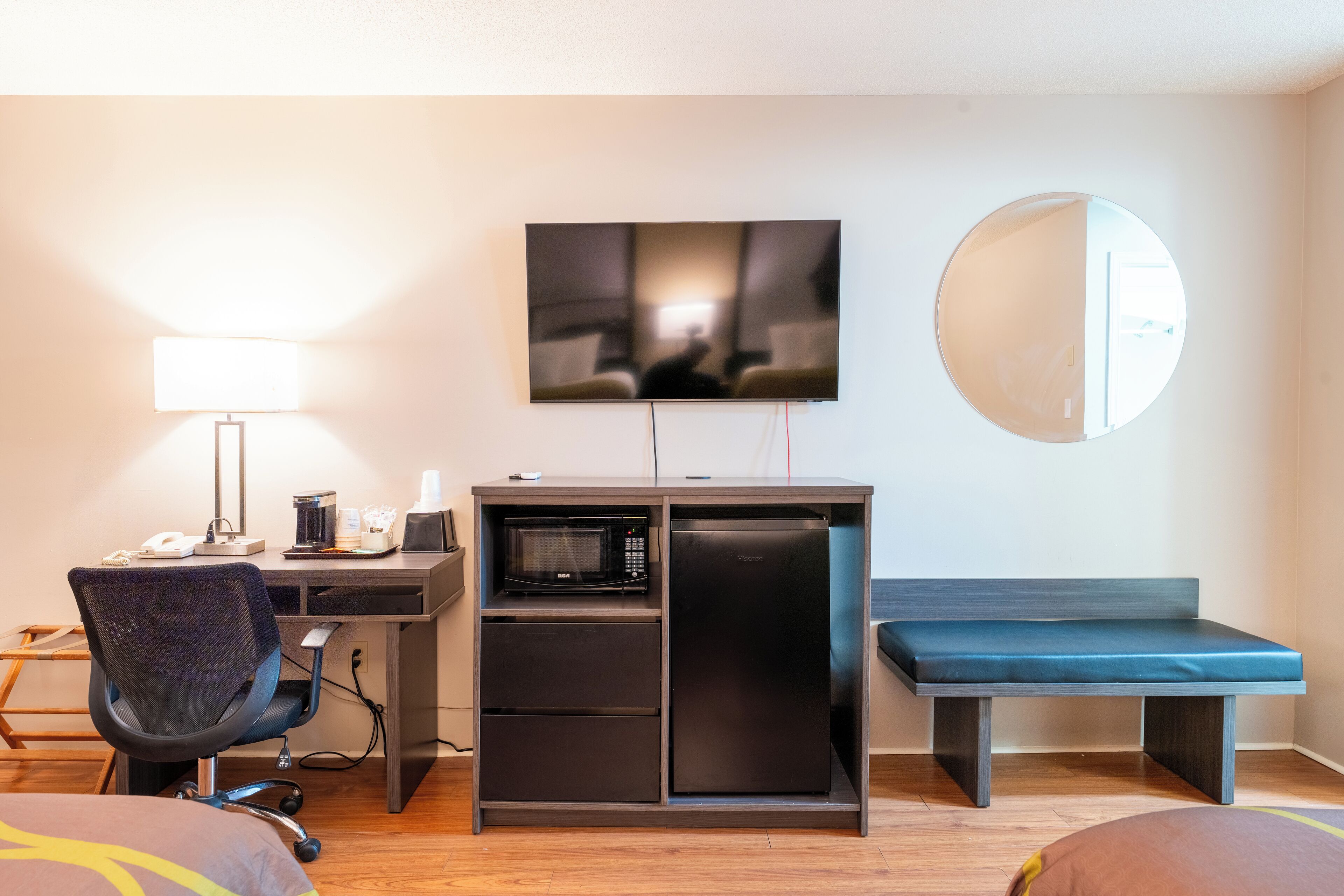 A compact hotel room with a desk, microwave, and seating area.