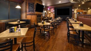 A restaurant with wooden booths, tables, and a bar area. - Super 8 by Wyndham Gananoque/Country Squire Resort (Gananoque)