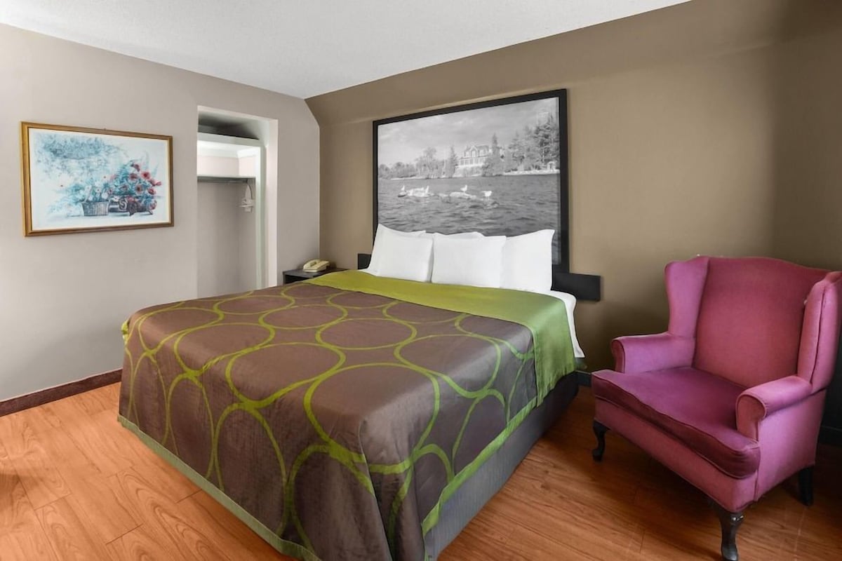 Habitación de hotel con cama, una silla, un cuadro y vistas a un cuerpo de agua.