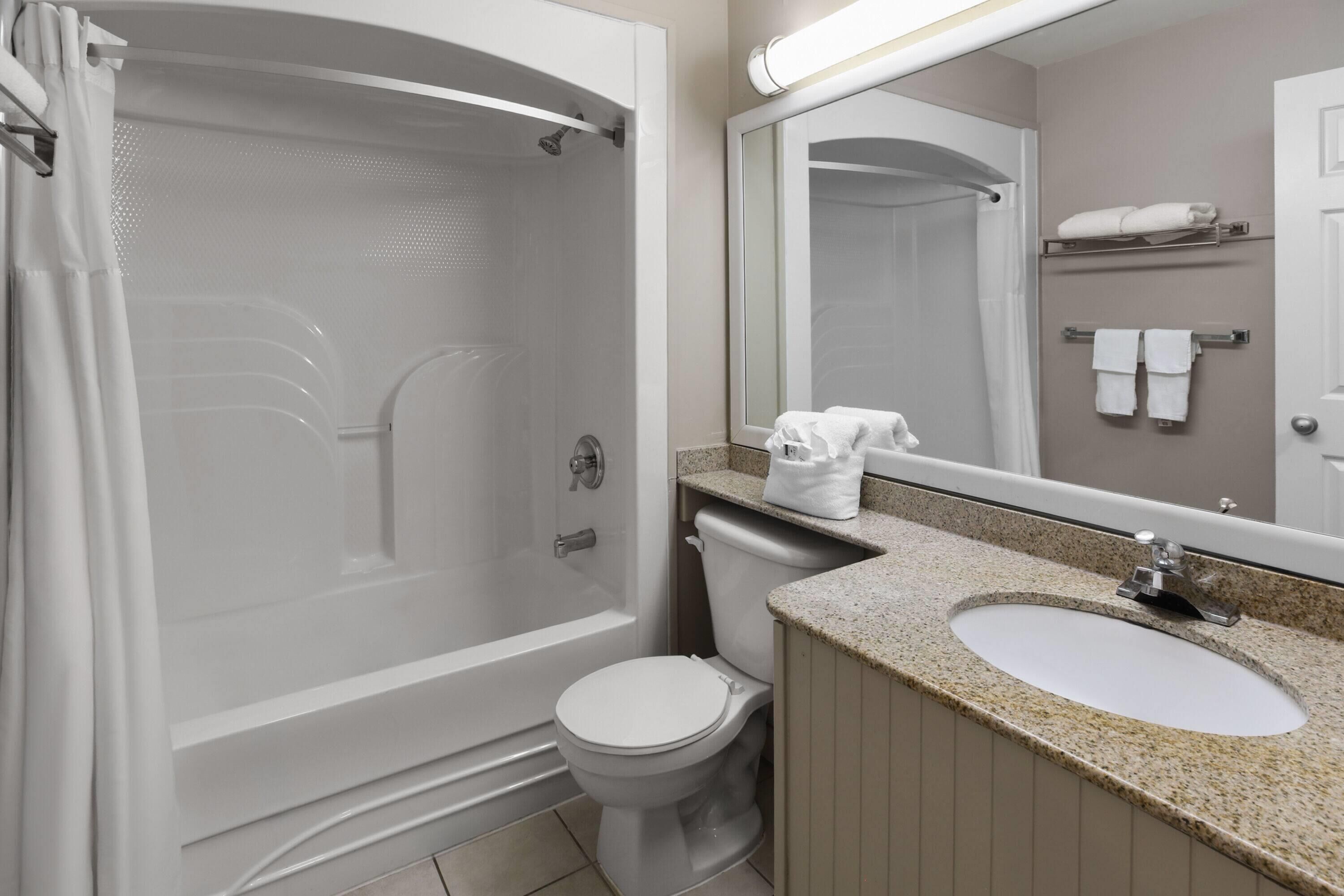A bathroom with a bathtub, toilet, sink, and a mirror.