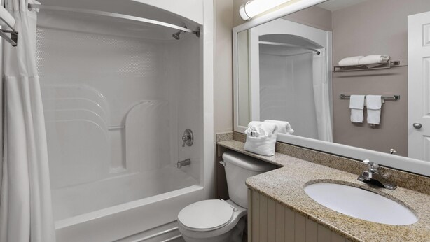 A bathroom with a bathtub, toilet, sink, and a mirror. - Super 8 by Wyndham Gananoque/Country Squire Resort (Gananoque)