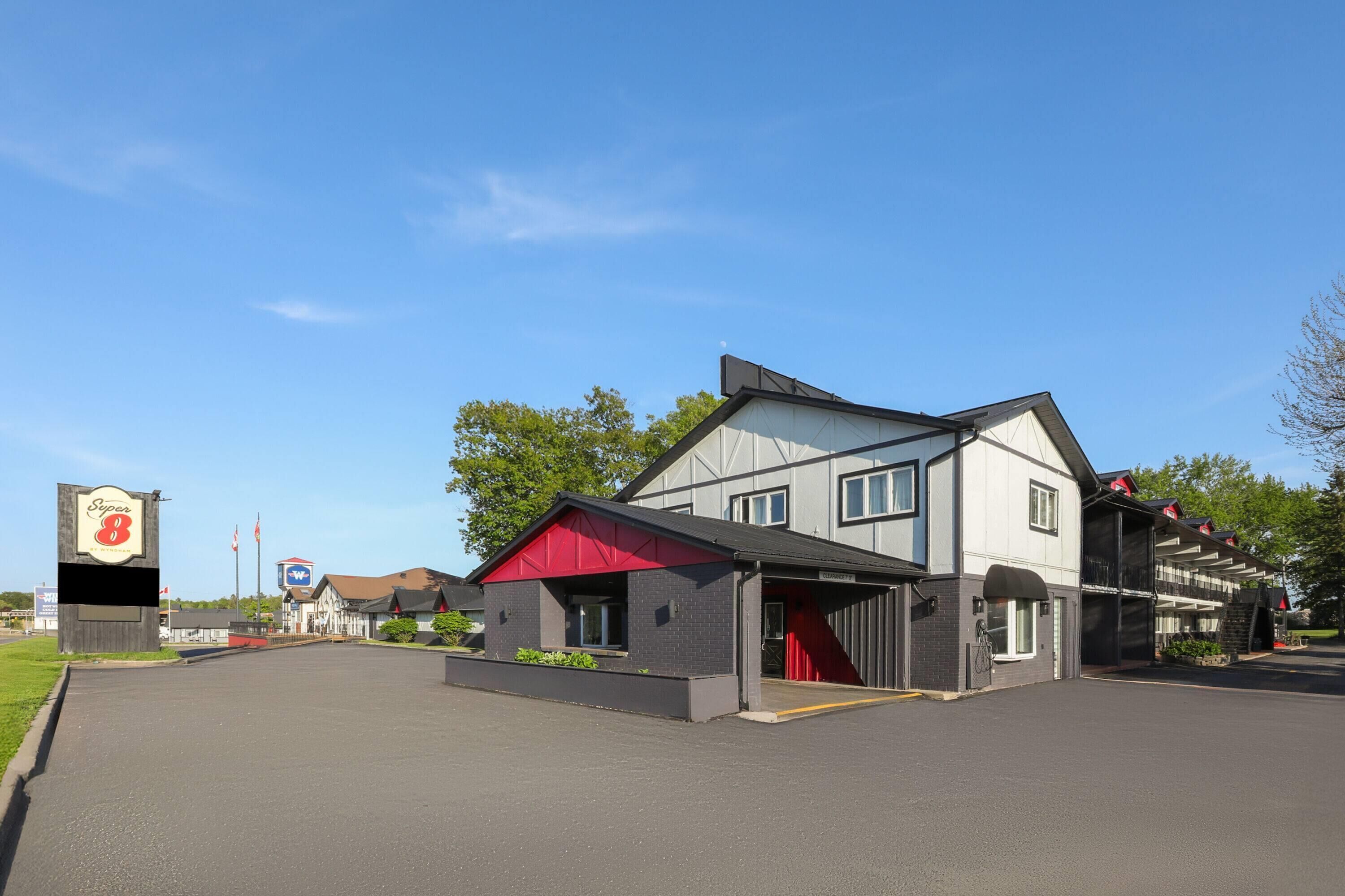 A two-story building with a red awning, a signboard, and a parking lot.