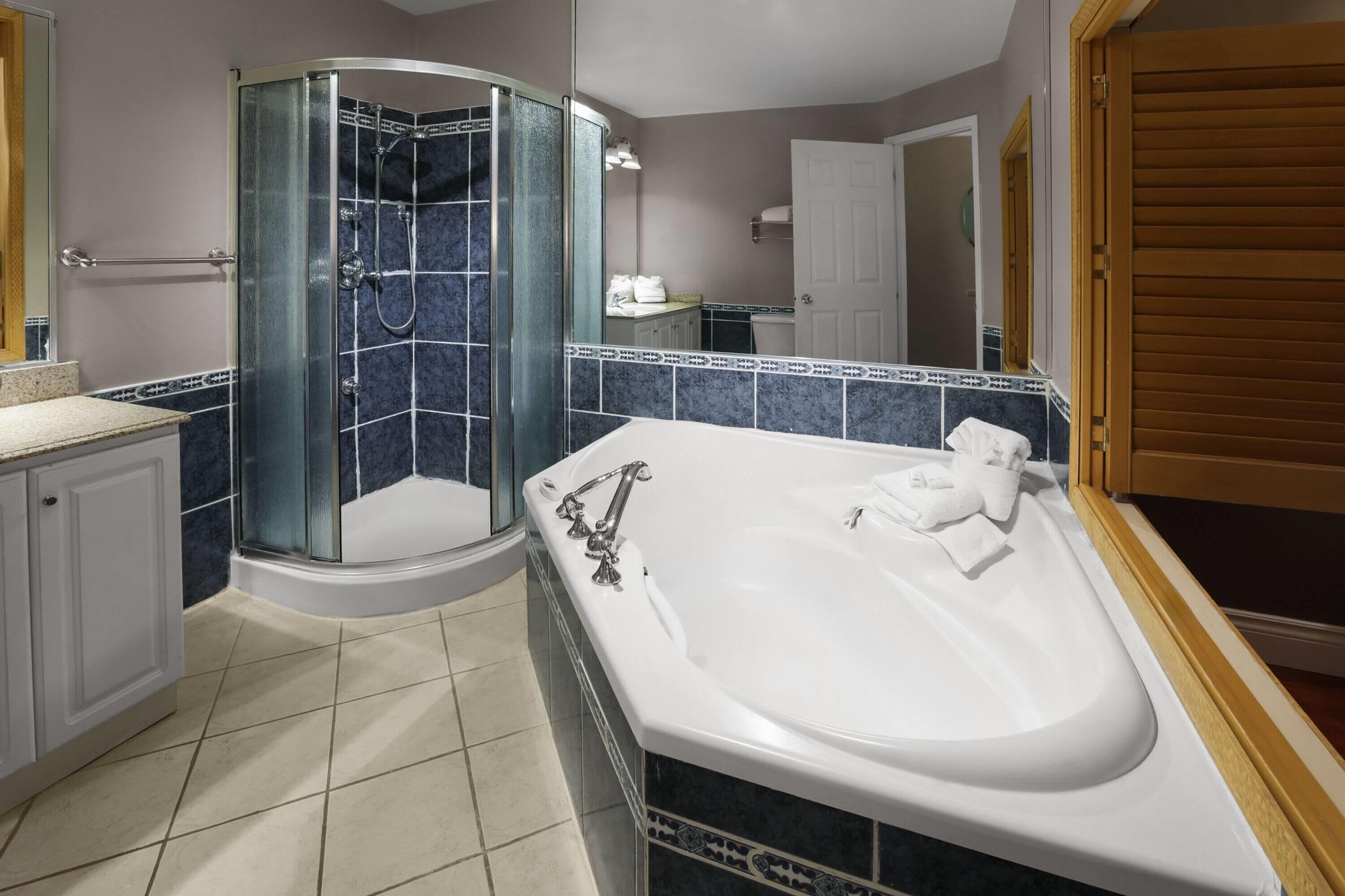 Ein Badezimmer mit Duschkabine, freistehender Badewanne und Fliesenboden.