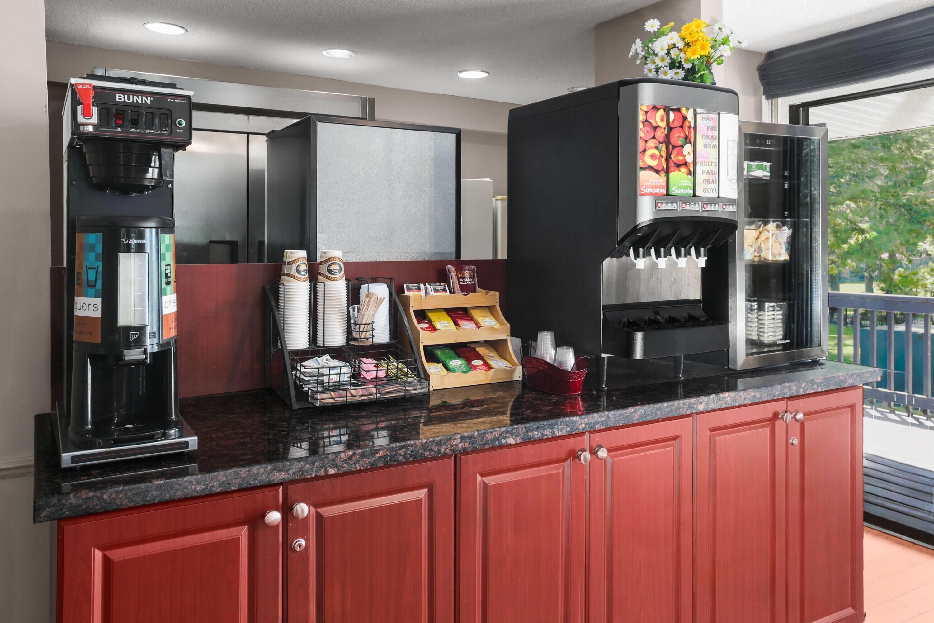 A coffee station with a Bunn coffee machine, a beverage dispenser, and a selection of coffee pods.