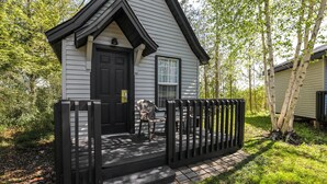 A small, single-story house with a black door, a window, and a porch with a black railing. - Super 8 by Wyndham Gananoque/Country Squire Resort (Gananoque)