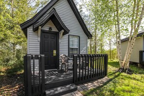 A small, single-story house with a black door, a window, and a porch with a black railing. - Super 8 by Wyndham Gananoque/Country Squire Resort (Gananoque)